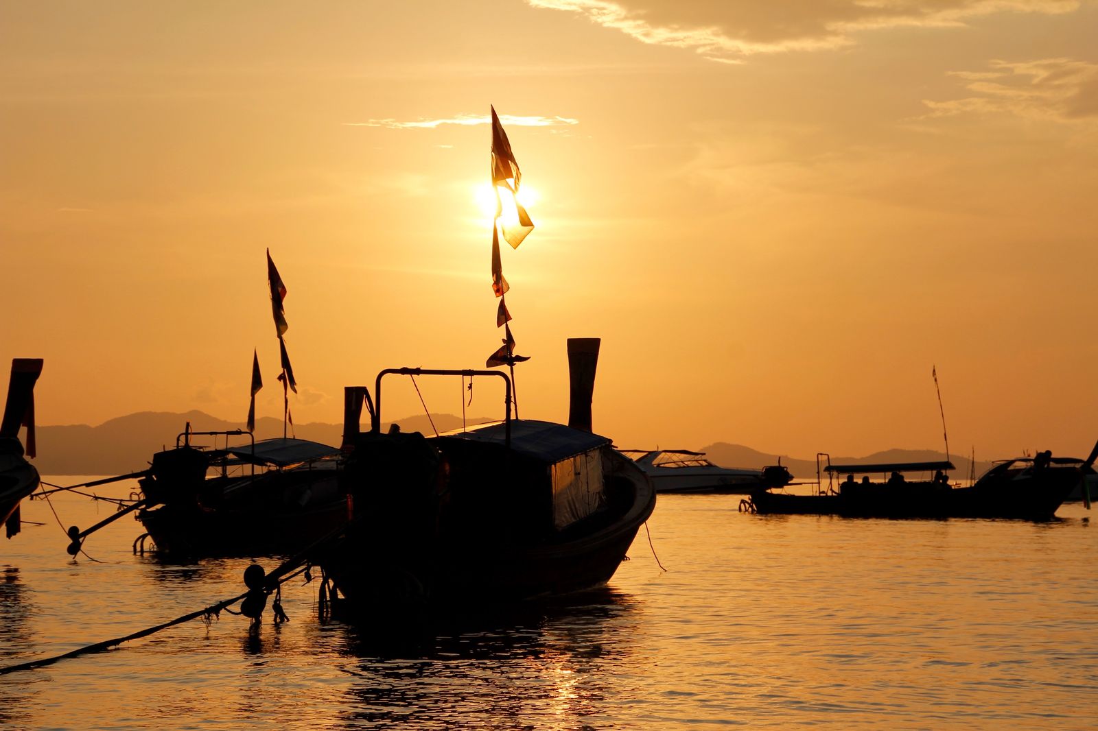 Boat silhouettes at golden hour in a calm harbor